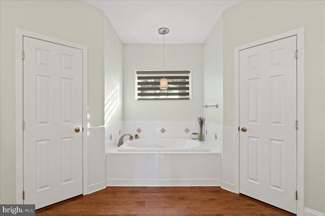 bathroom with hardwood / wood-style floors and tiled tub