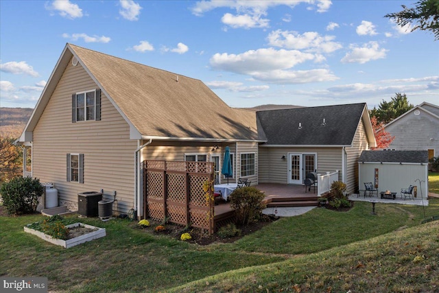 rear view of house featuring a lawn, french doors, a wooden deck, and central AC