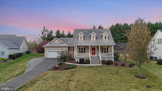 cape cod-style house with a lawn, covered porch, and a garage