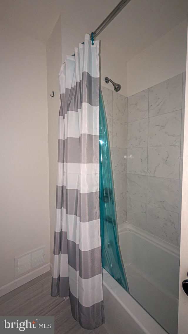 bathroom featuring hardwood / wood-style floors and shower / bathtub combination with curtain