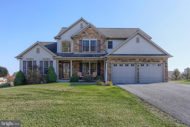 view of front of house with a porch, a front yard, and a garage