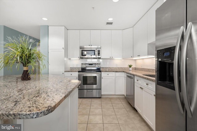 kitchen featuring appliances with stainless steel finishes, white cabinetry, light stone counters, and light tile patterned floors