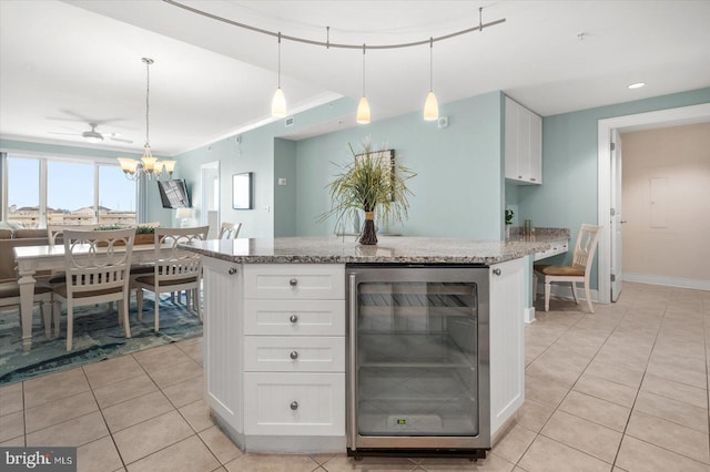 kitchen featuring white cabinets, light stone countertops, decorative light fixtures, and beverage cooler