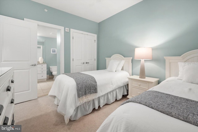 bedroom featuring connected bathroom, light carpet, and a closet