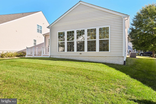 rear view of house with central AC and a lawn