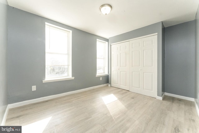 unfurnished bedroom with a closet, multiple windows, and light wood-type flooring