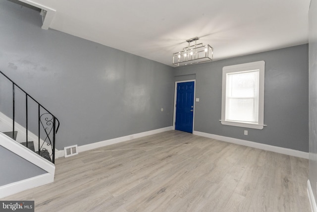 unfurnished room with an inviting chandelier and light wood-type flooring