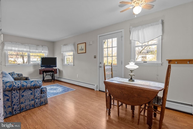 living room with baseboard heating, light hardwood / wood-style flooring, and ceiling fan