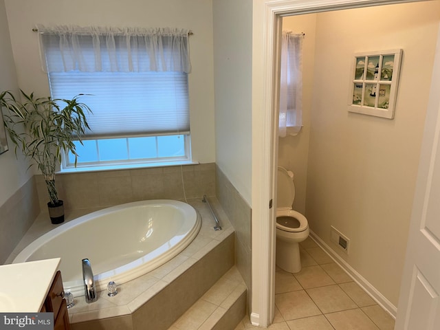 bathroom with vanity, a relaxing tiled tub, toilet, and tile patterned flooring