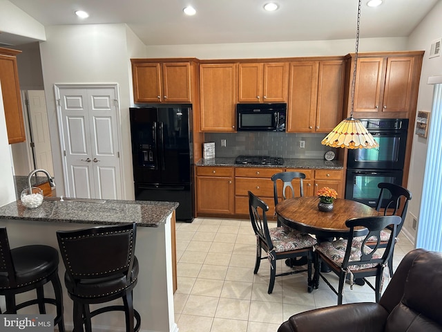 kitchen featuring sink, black appliances, light tile patterned floors, and dark stone countertops