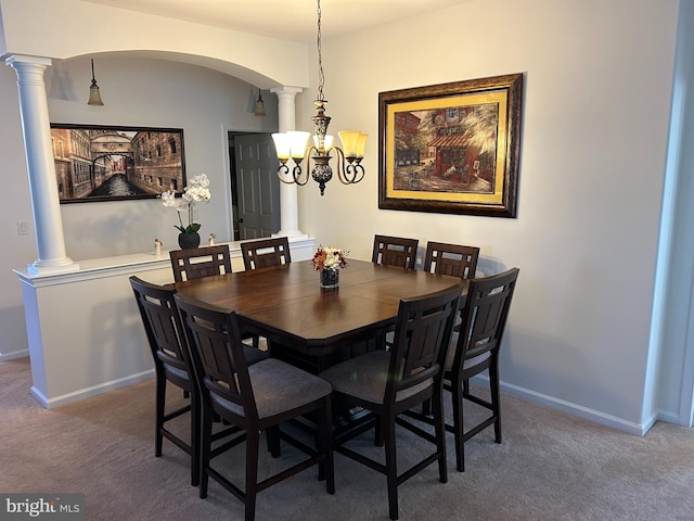 dining area featuring a notable chandelier, dark colored carpet, and ornate columns