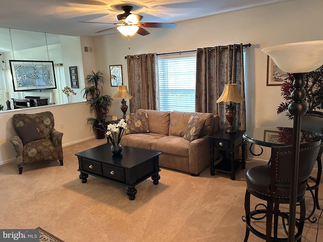 living room featuring ceiling fan with notable chandelier and light colored carpet