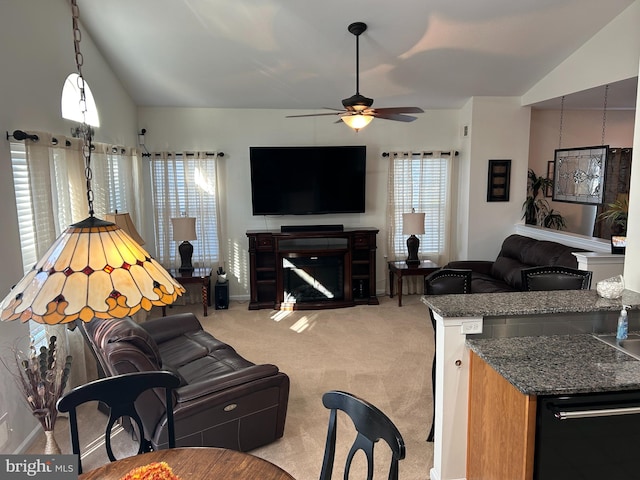 carpeted living room with ceiling fan and vaulted ceiling