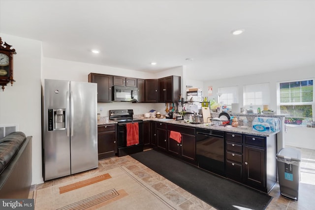 kitchen featuring sink, light stone countertops, black appliances, and dark brown cabinetry