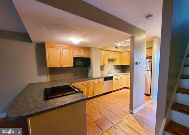 kitchen featuring light brown cabinets, kitchen peninsula, tasteful backsplash, light hardwood / wood-style flooring, and black appliances