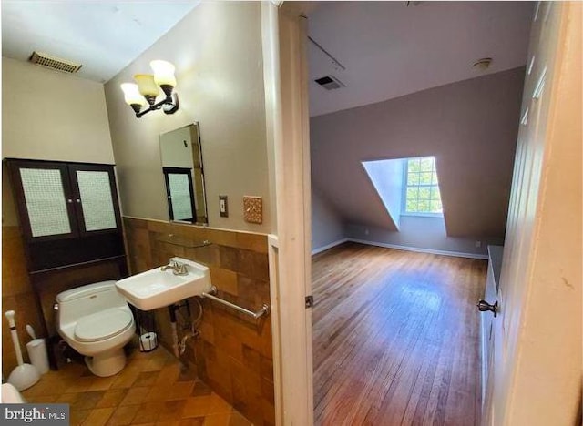 bathroom featuring wood-type flooring, sink, french doors, toilet, and vaulted ceiling