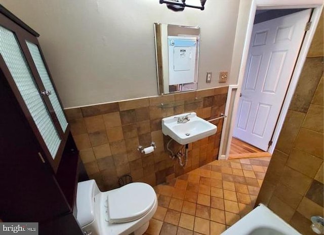 bathroom with sink, a bath, toilet, tile walls, and tile patterned flooring