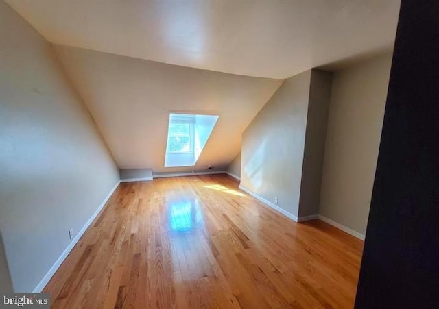 additional living space featuring light hardwood / wood-style floors and lofted ceiling