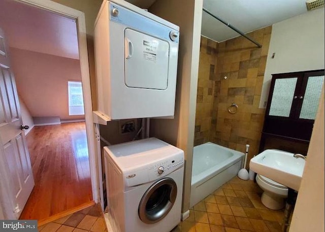 clothes washing area featuring french doors, light hardwood / wood-style floors, and stacked washer and clothes dryer