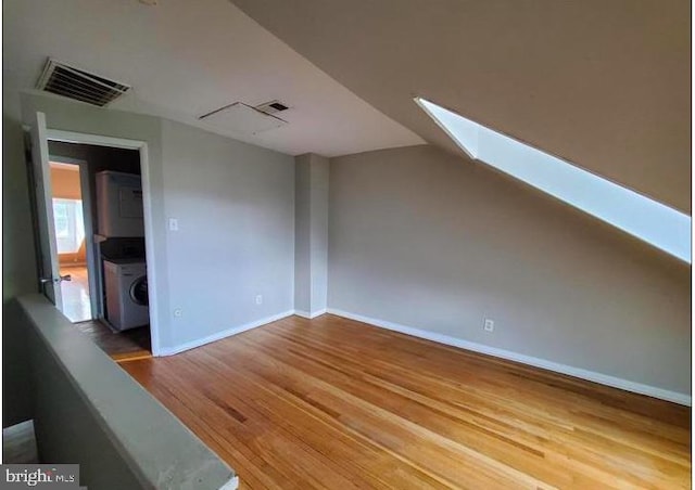 additional living space with washer / dryer, wood-type flooring, and a skylight