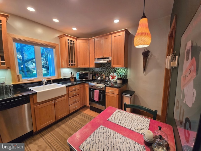 kitchen featuring sink, appliances with stainless steel finishes, pendant lighting, and backsplash