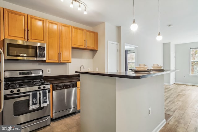 kitchen featuring appliances with stainless steel finishes, light wood-type flooring, and pendant lighting