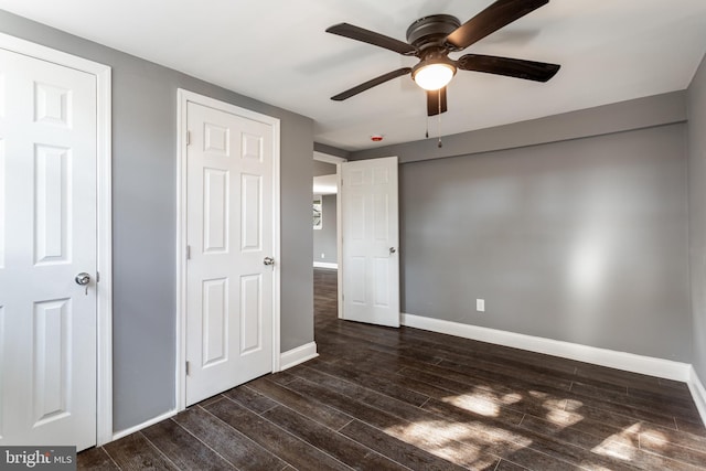 unfurnished bedroom featuring two closets, dark hardwood / wood-style floors, and ceiling fan