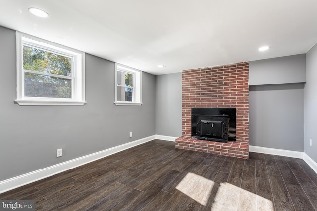 unfurnished living room with dark wood-type flooring and a brick fireplace