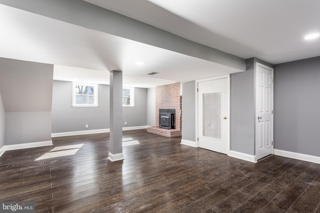 basement featuring a wood stove and dark hardwood / wood-style floors