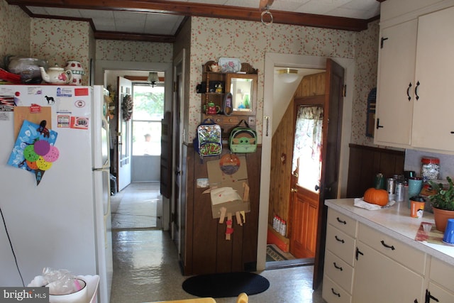 kitchen featuring concrete floors, wood walls, ceiling fan, white cabinets, and white refrigerator