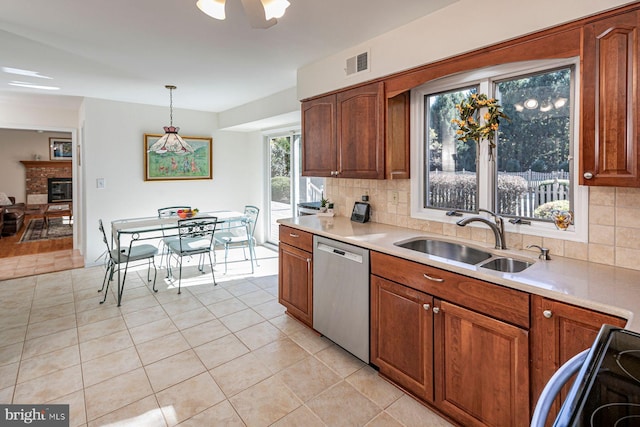 kitchen featuring dishwasher, backsplash, sink, pendant lighting, and a fireplace