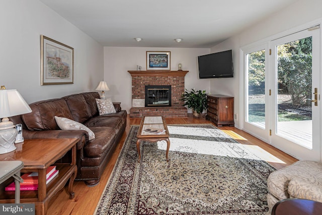 living room with light wood-type flooring and a brick fireplace