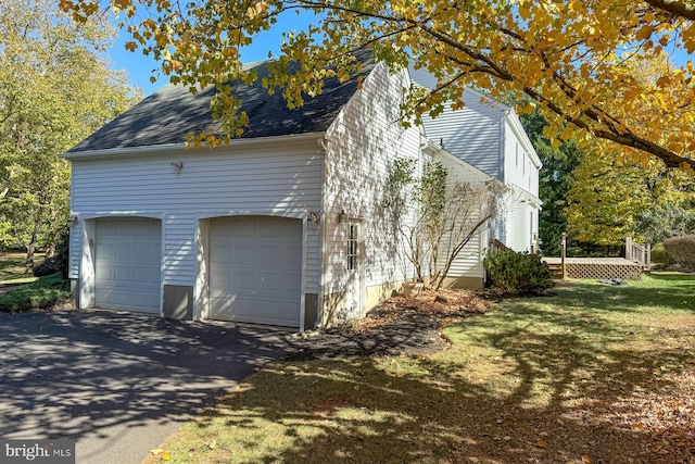 view of side of property featuring a garage and a lawn