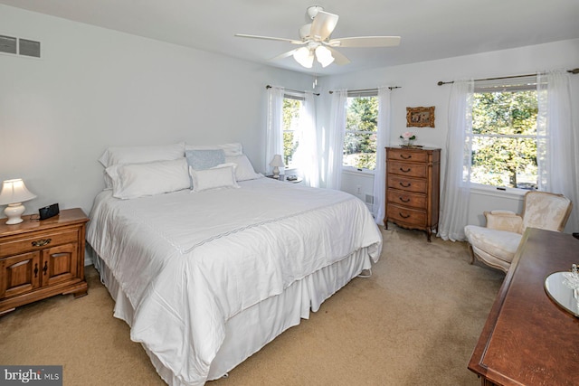 carpeted bedroom featuring multiple windows and ceiling fan