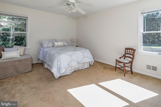 bedroom with multiple windows, light colored carpet, and ceiling fan