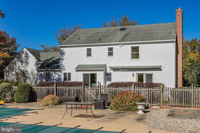 back of property featuring a patio and a covered pool