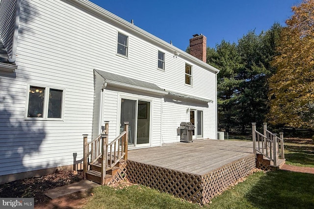 rear view of property with a wooden deck, central air condition unit, and a lawn