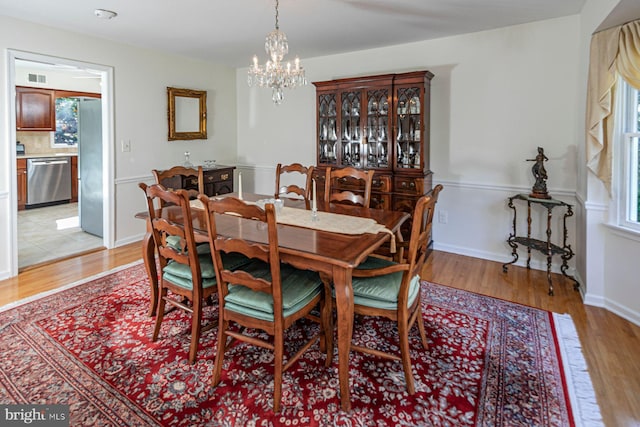 dining space featuring light hardwood / wood-style floors and a notable chandelier