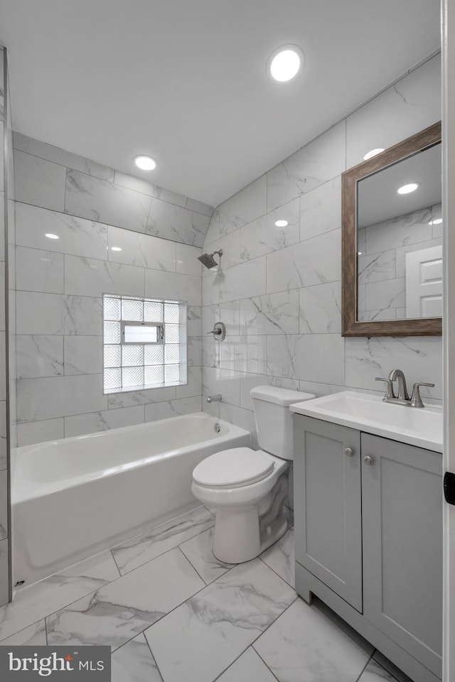 full bathroom featuring vanity, toilet, tile walls, and tiled shower / bath