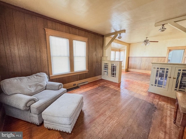 sitting room with ceiling fan, wooden walls, and hardwood / wood-style floors