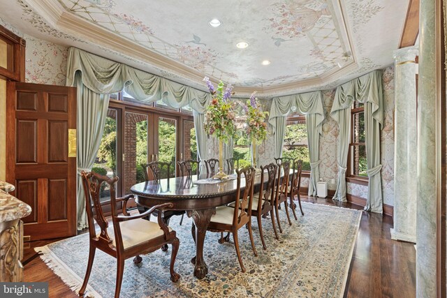 dining room featuring wood finished floors, wallpapered walls, ornamental molding, a raised ceiling, and french doors