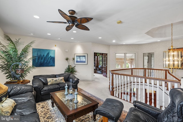 carpeted living room with ceiling fan with notable chandelier