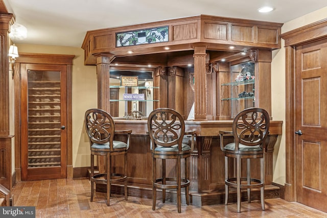 bar with wood finished floors, indoor wet bar, and baseboards