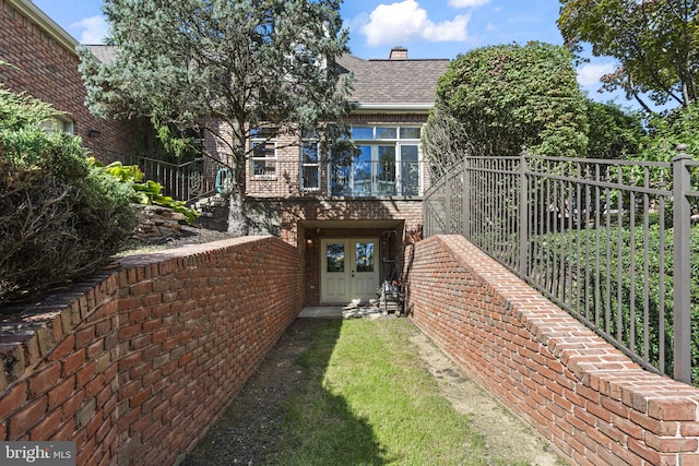 rear view of house featuring brick siding, fence, and a shingled roof