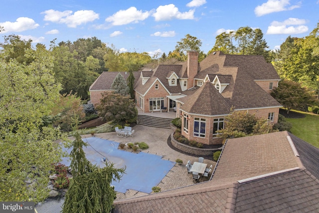 exterior space featuring a chimney, a patio, a shingled roof, and a deck