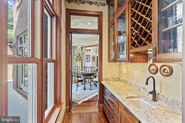 kitchen featuring sink, light stone counters, and dark hardwood / wood-style flooring