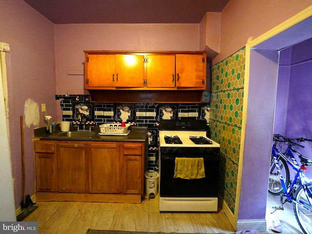 kitchen with light hardwood / wood-style floors, sink, backsplash, and white stove