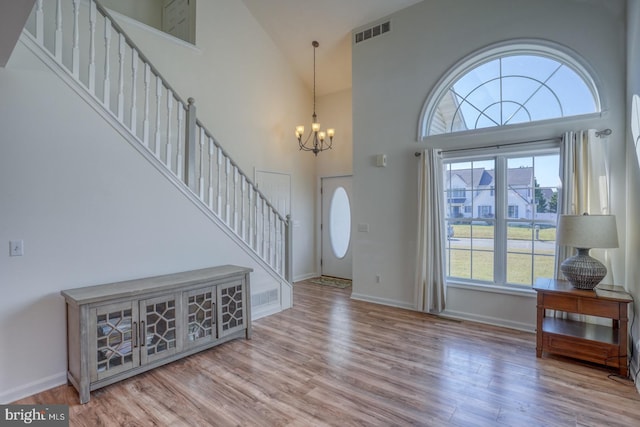 entryway featuring an inviting chandelier, light wood-type flooring, high vaulted ceiling, and plenty of natural light