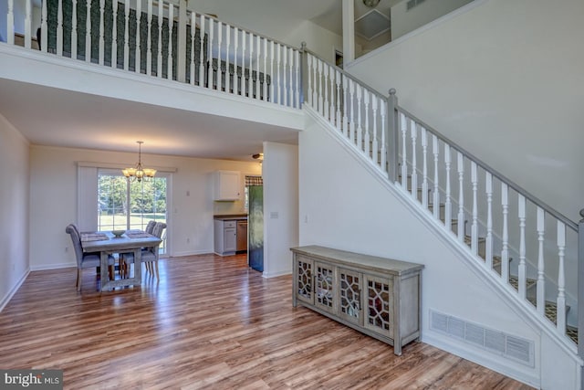 stairs featuring hardwood / wood-style floors, a notable chandelier, and a towering ceiling