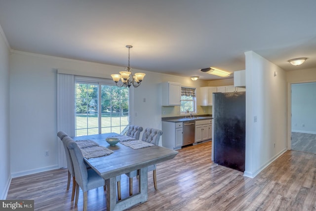 dining room featuring light hardwood / wood-style flooring, a chandelier, sink, and crown molding